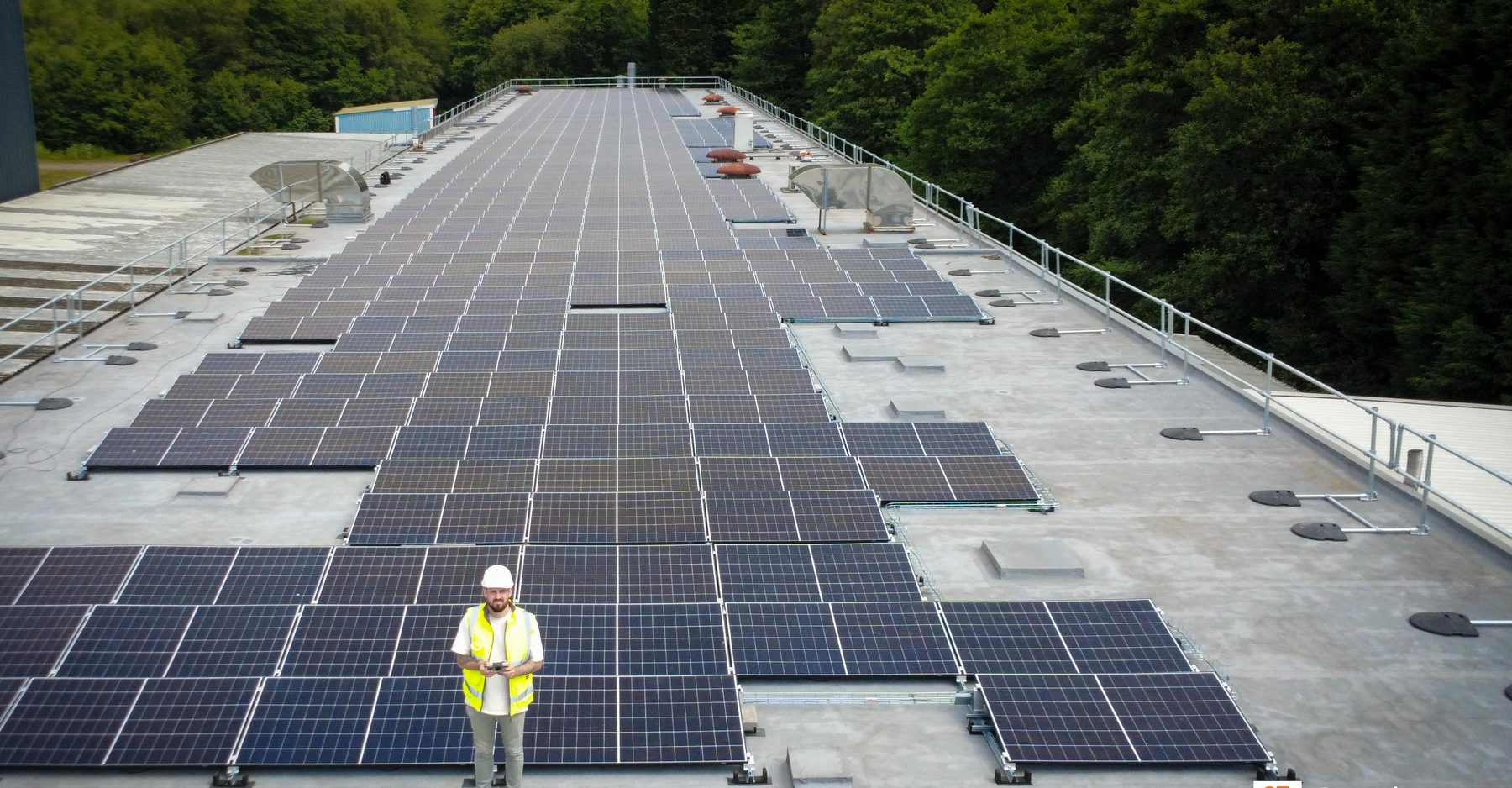 Aerial view of the 637 kW rooftop solar array at Irvin-GQ Parachutes, with an FLD engineer on the roof for scale